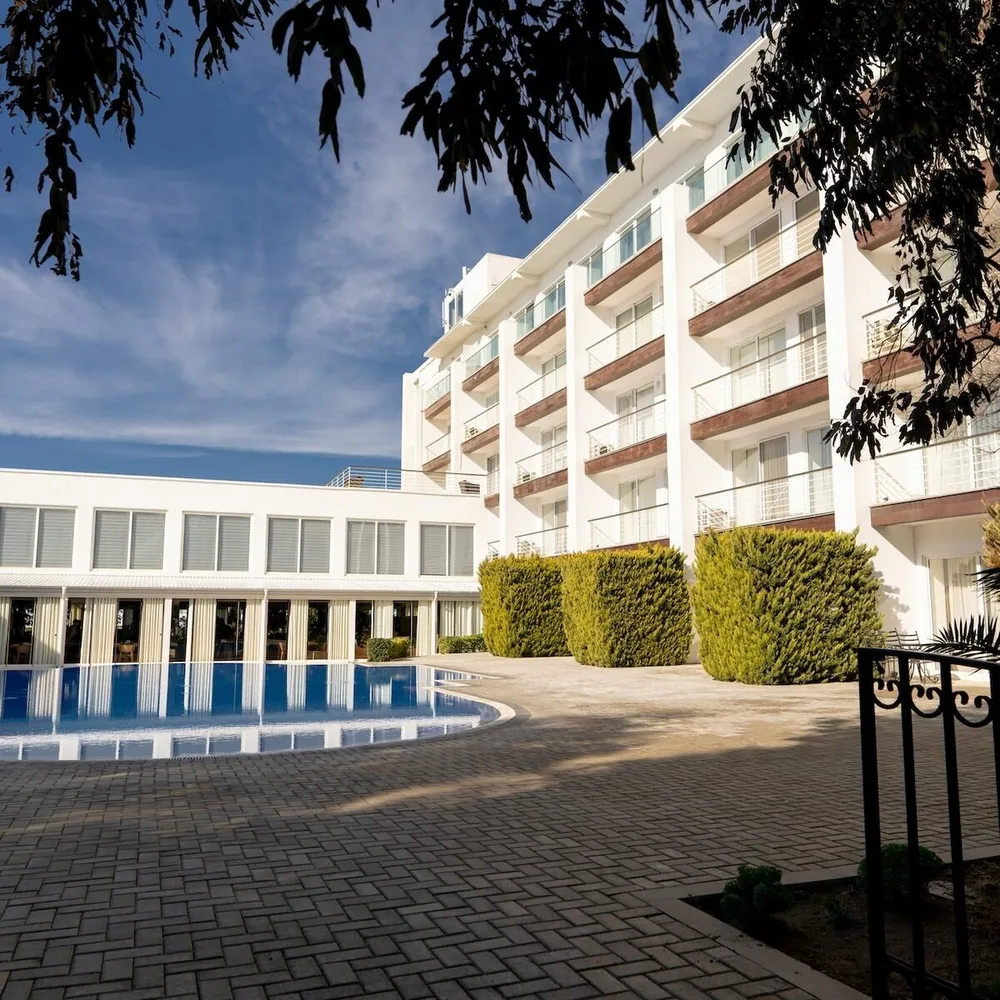 A white building with balconies and a pool in the courtyard