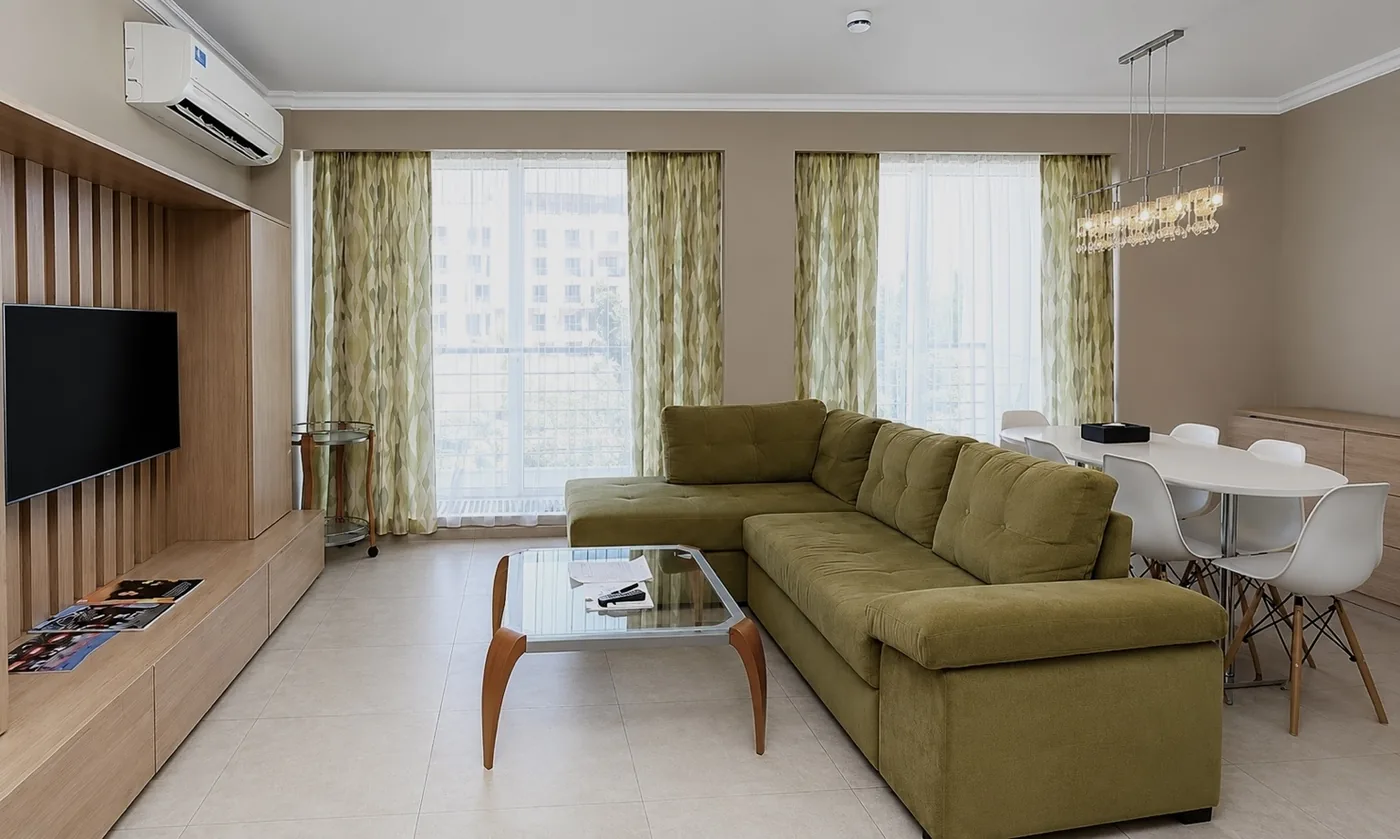 A living room with a corner sofa and a dining table
